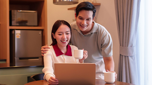 A couple look at a computer screen while drinking coffee