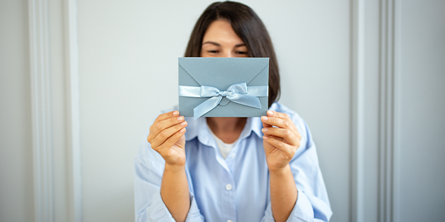 A woman holding an envelope with a ribbon around it