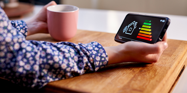 A hand holding a mug and a mobile phone