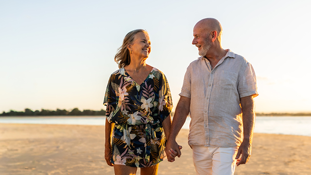 elderly couple walking on the beach at sunrise