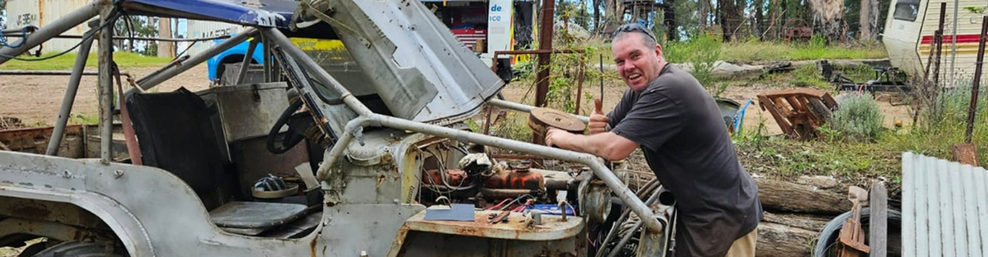 Side view of a man standing in front of his fixer upper buggy smiling.