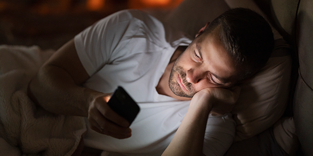 Man looking at his phone while in bed