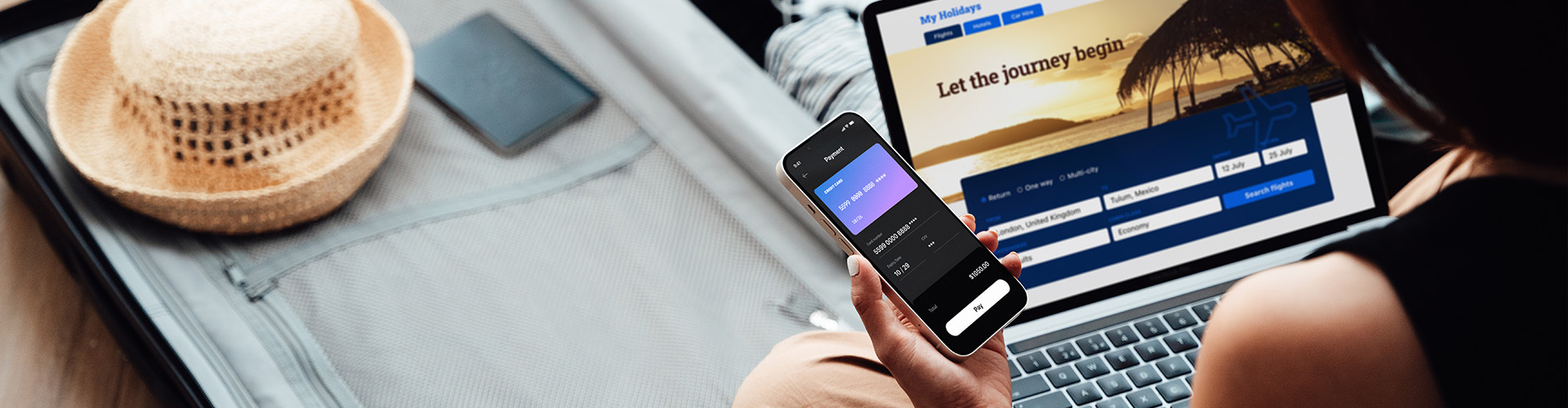 Over the shoulder view of young woman booking a flight via laptop and smartphone for vacation