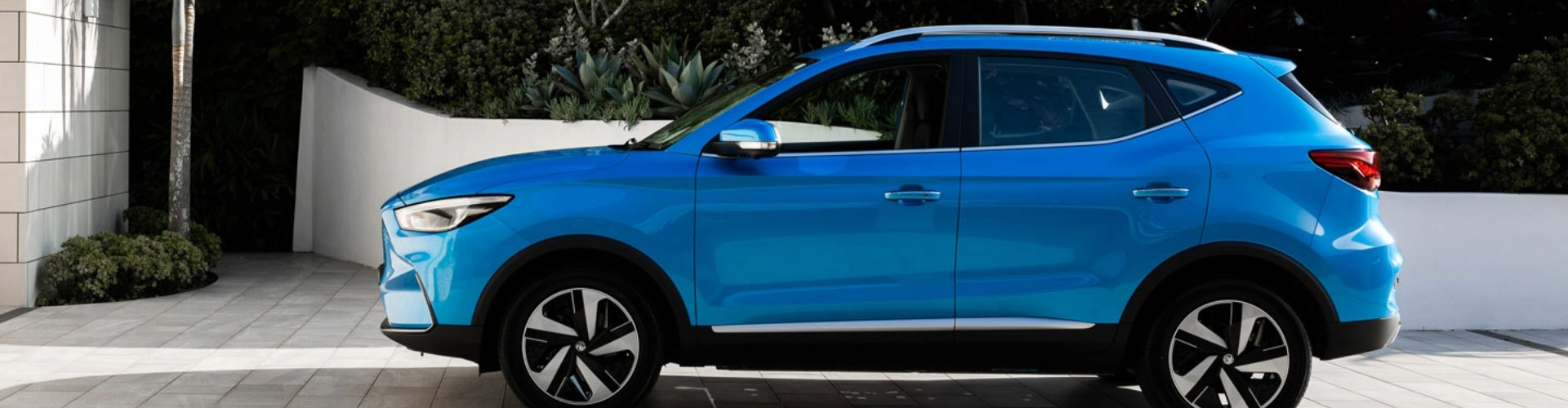Side view of an MG ZS EV parked in a white concrete driveway.
