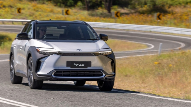 Front view of a silver, 2024 Toyota BZ4x driving along a road.