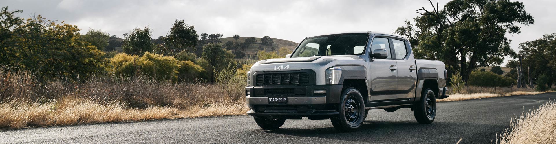 Grey Kia Tasman in front of bushland