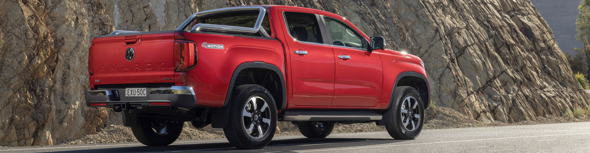 Red Volkswagen Amarok in front of a natural rock wall