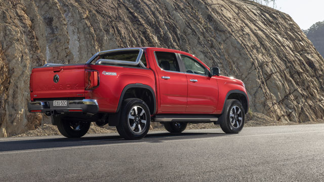 Red Volkswagen Amarok in front of a natural rock wall