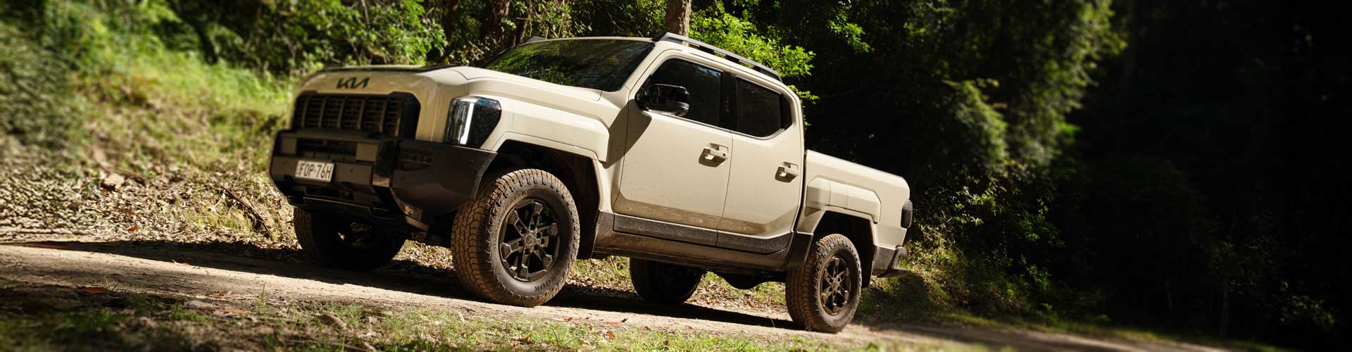 2025 Kia Tasman parked on a bush road
