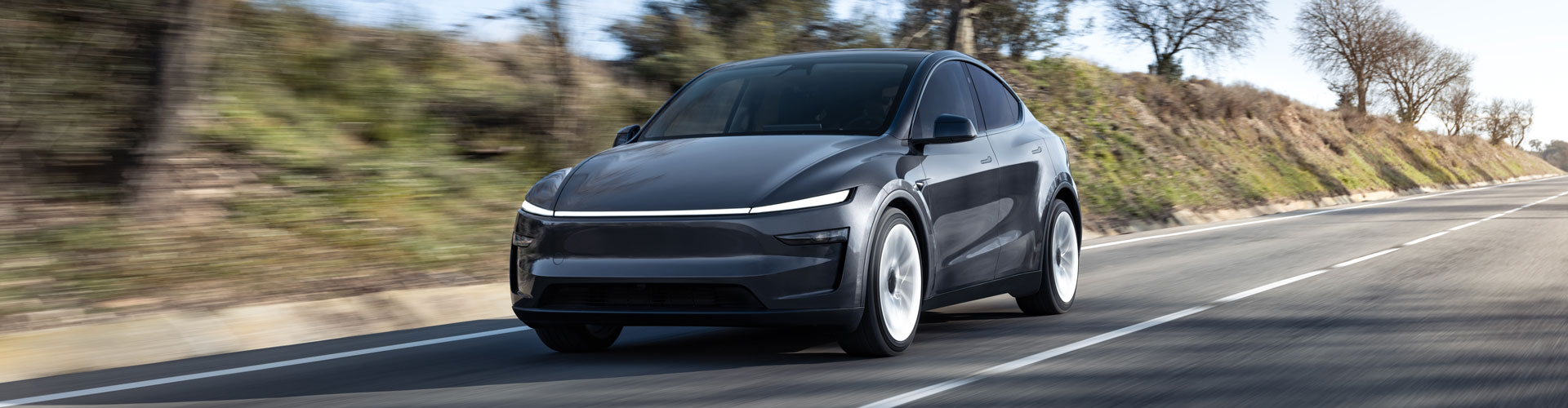 Grey Tesla Model Y driving on country road