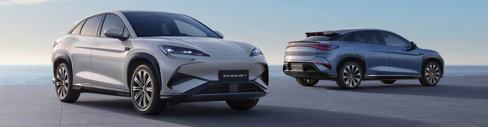 Two silver BYD Sealion 7 SUVs parked in front of a blank background