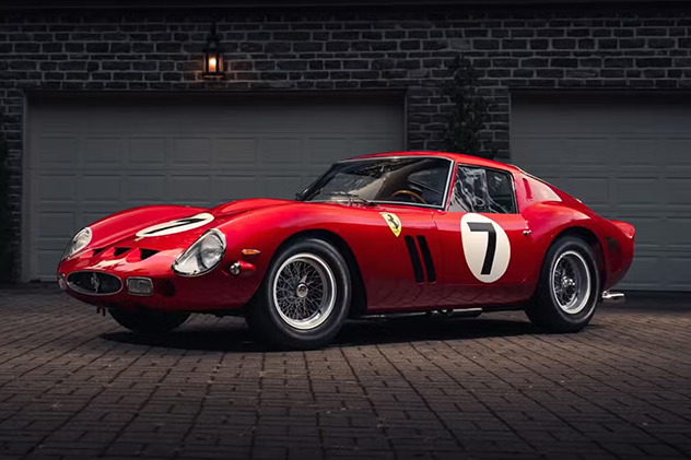 A red Ferrari 250 parked in front of a garage