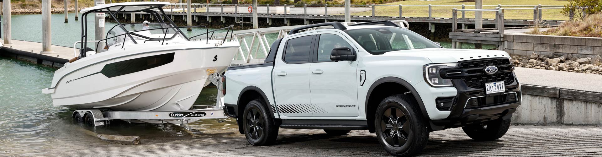 A white Ford Ranger PHEV pulls a boat up a ramp