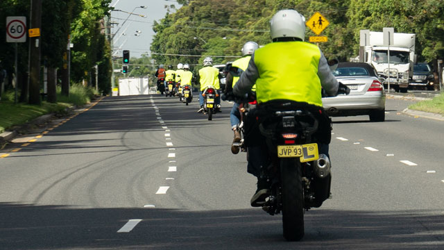 A learner cyclist wearing a hivis jacket on a NSW road