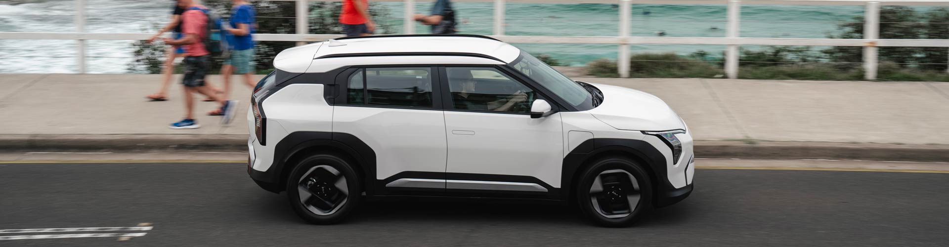 White Kia EV3 driving in front of the beach