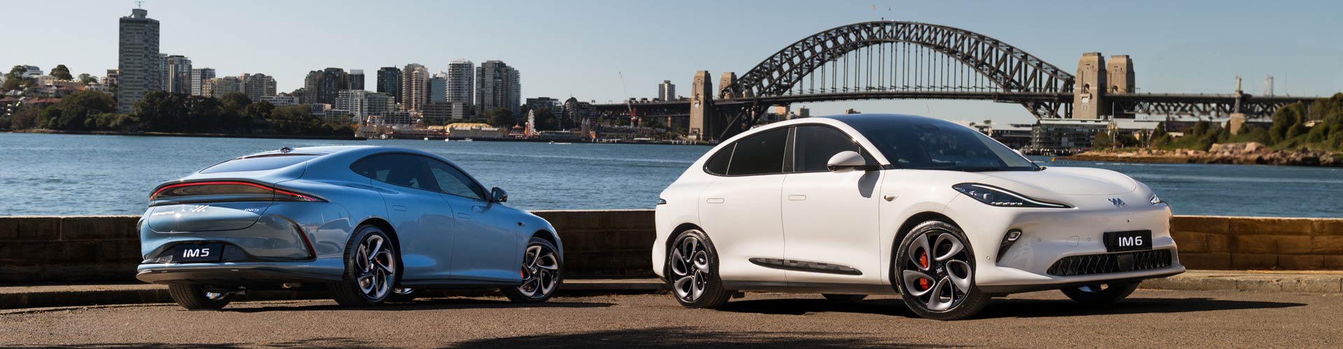 Blue MG IM6 and white IM5 parked with city and harbour bridge in the background