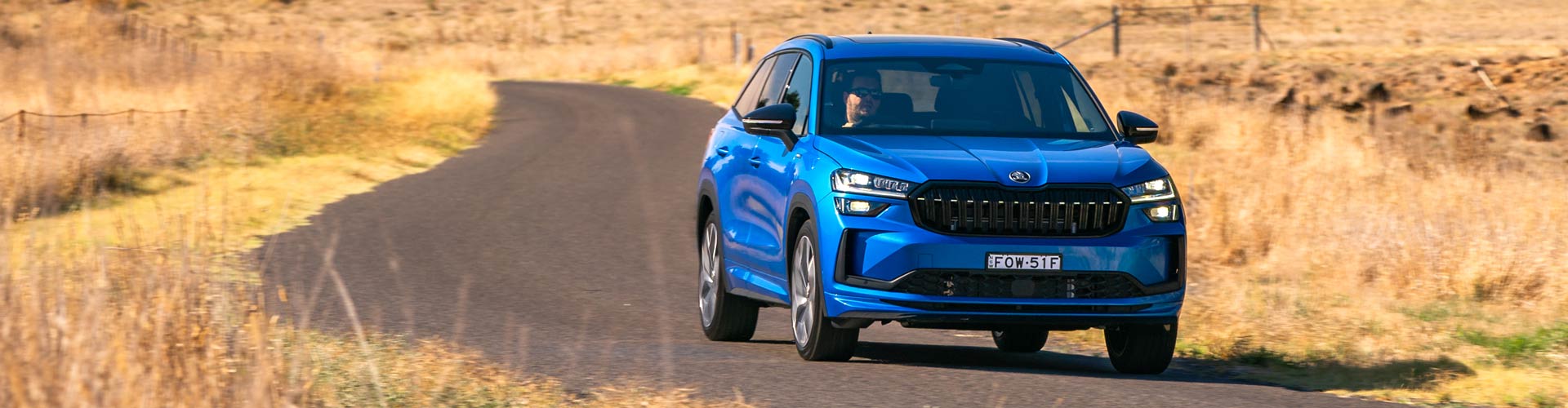 Front view of a blue 2025 Skoda Kodiaq on a country road