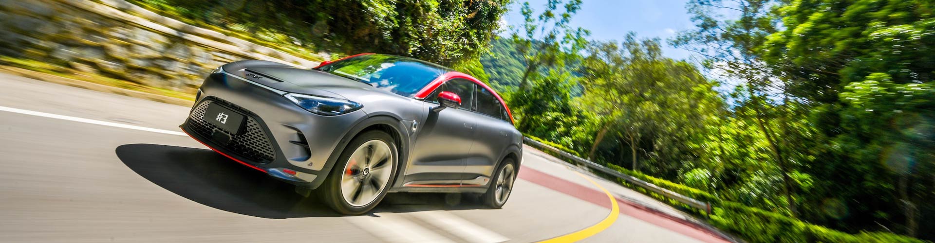 A front angle view of a two-tone dark silver with red accent Smart #3 Brabus on the road