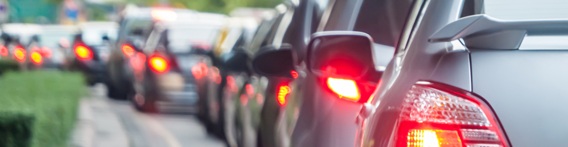 Rear view of a line of cars in road traffic with their break lights on.