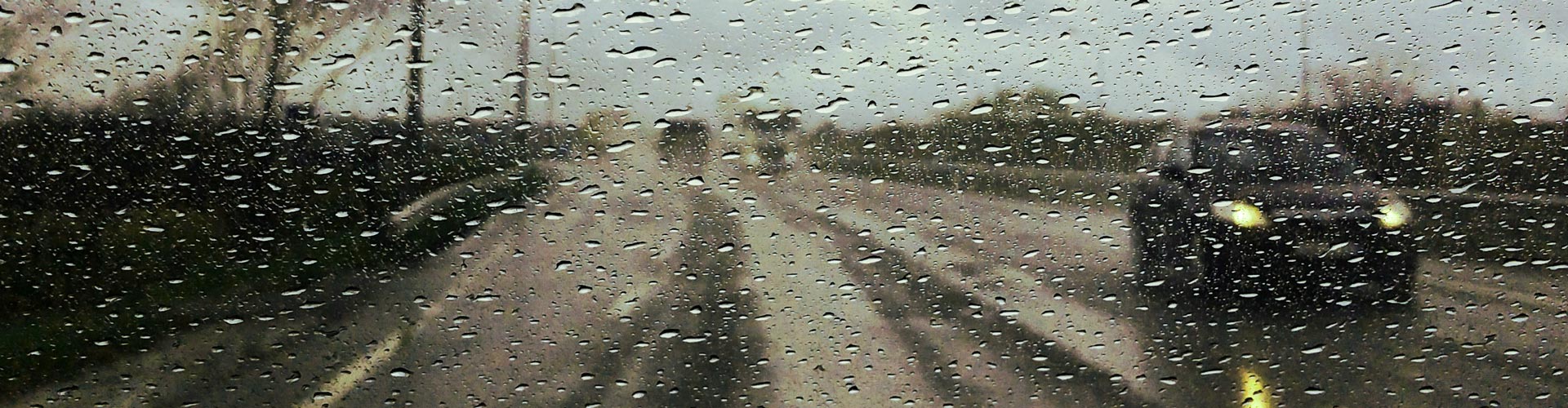 A car on a road seen through a wet window screen of a car on a rainy day