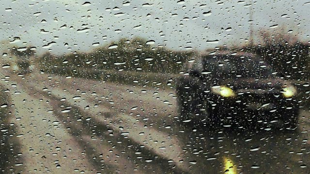 A car on a road seen through a wet window screen of a car on a rainy day