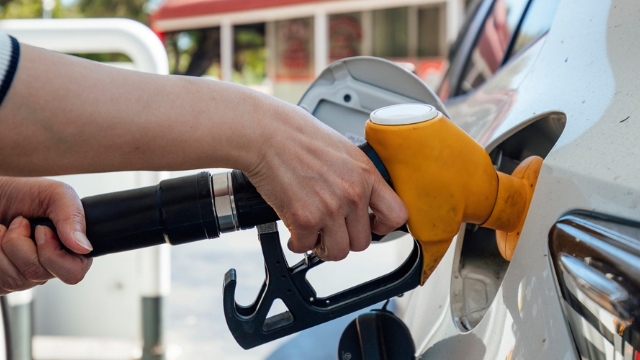 close up of woman's hand putting yellow fuel nozzle into her car