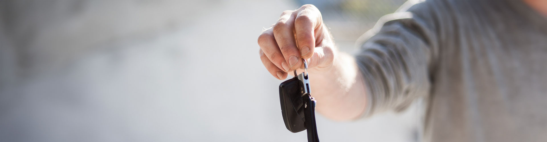 A closeup shot of a hand holding a set of car keys with a blurred background