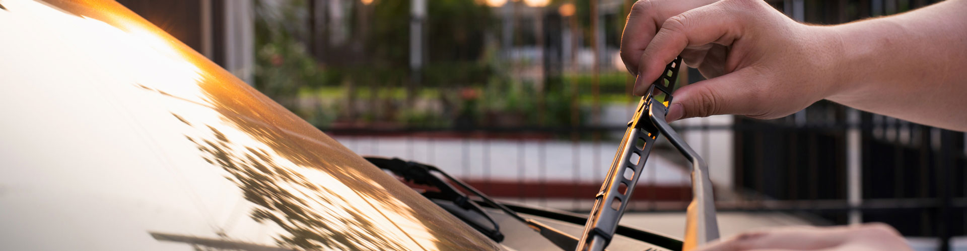 Closeup of hands changing a wiper blade on a car