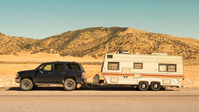 Black SUV towing a heavy caravan in the desert