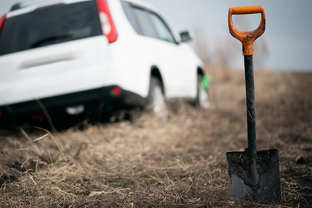 White car bogged in the background with a shovel in focus