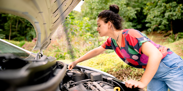 A  woman checking her car battery