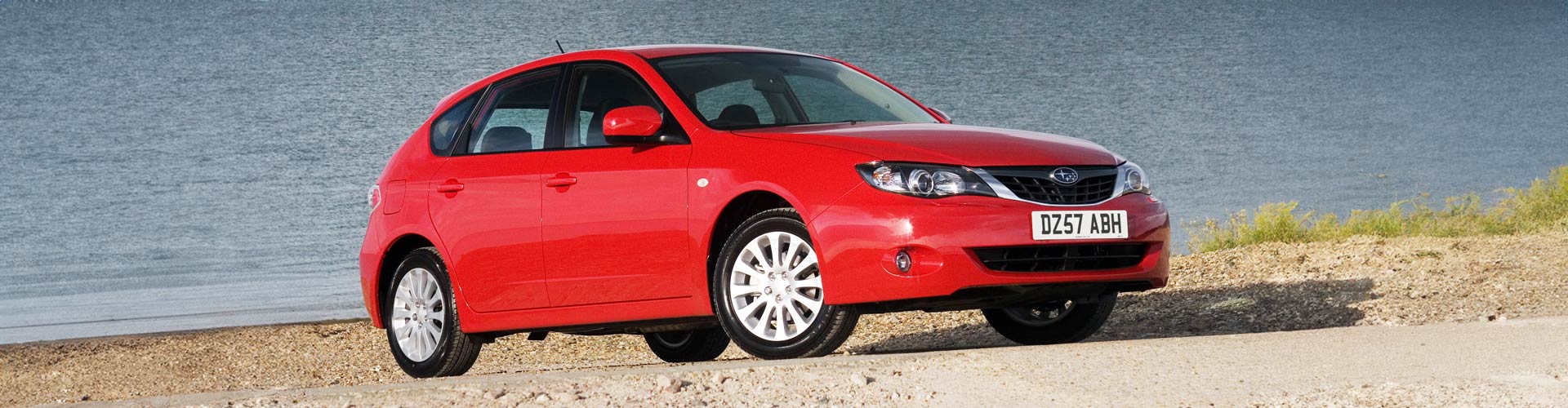 Red 2007 Subaru Impreza RS parked near a shoreline