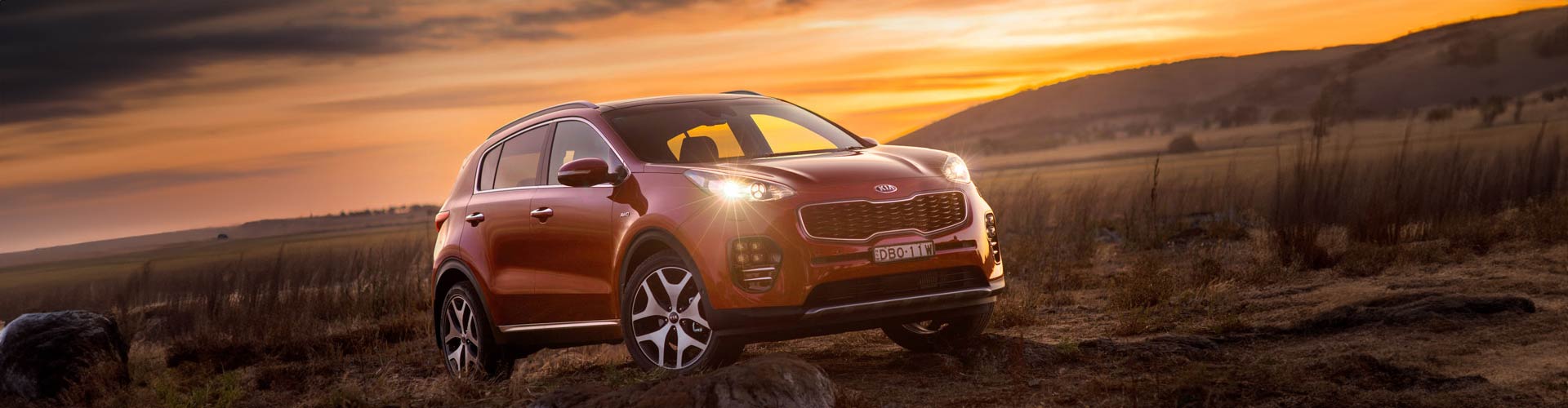 Red 2016 Kia Sportage Platinum parked in field at sunset