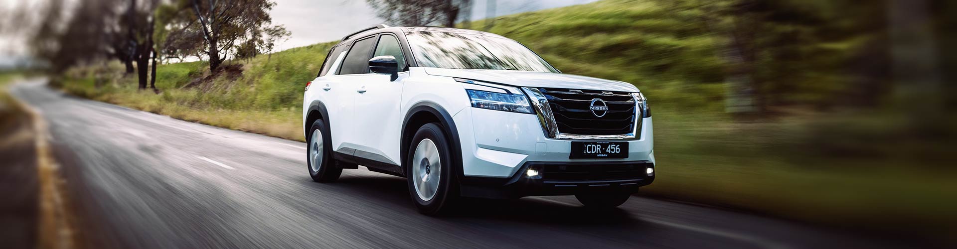 White 2023 Nissan Pathfinder driving