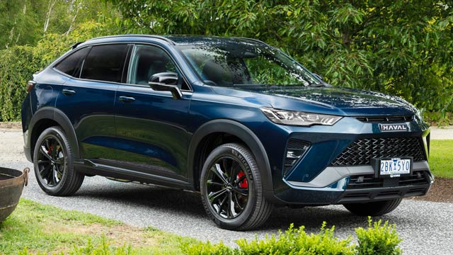 2025 GWM Haval H6GT PHEV parked in driveway surrounded by green plants