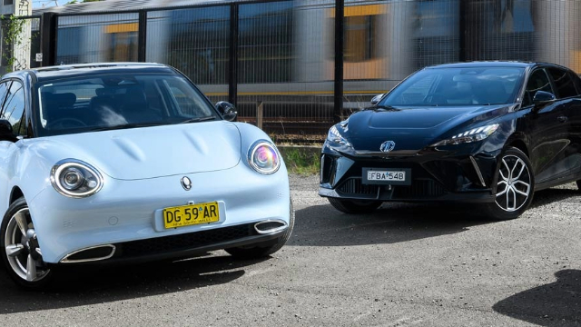 Three cars parked next to each other in front of a train line.