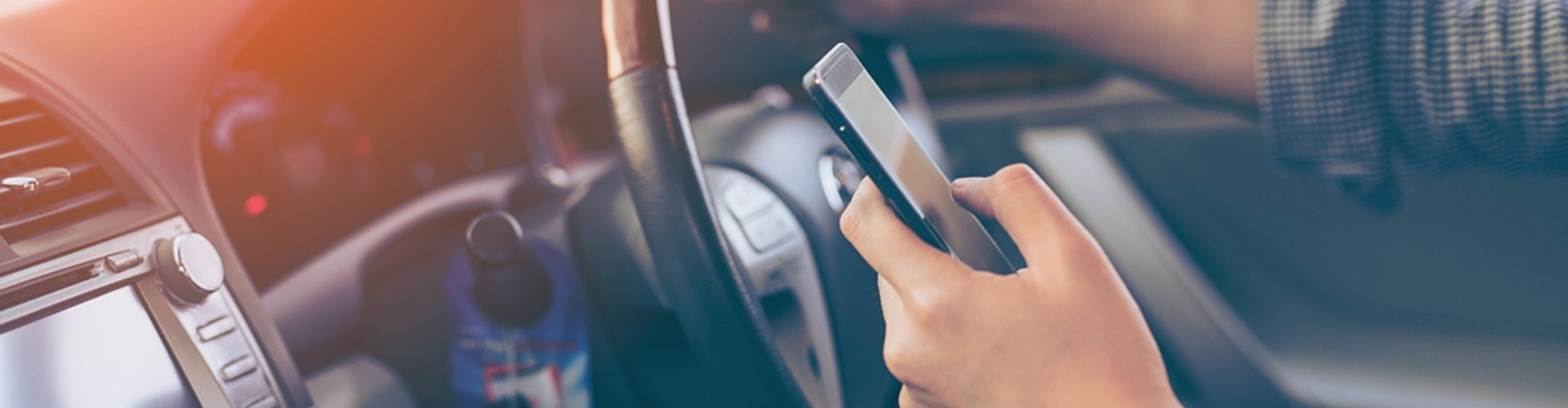A driver steers with one hand while using a mobile phone with the other.