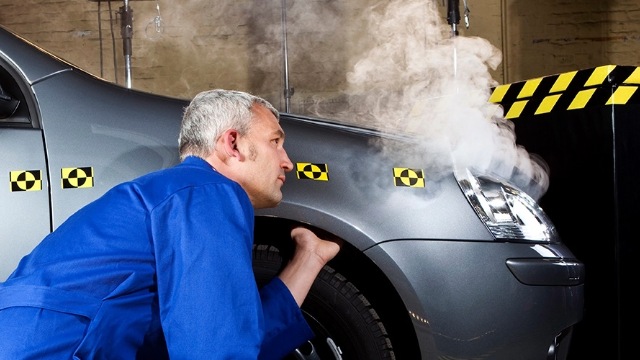 A technician examines a vehicle in a crash-test environment