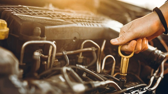Side view of a hand holding an oil dipstick
