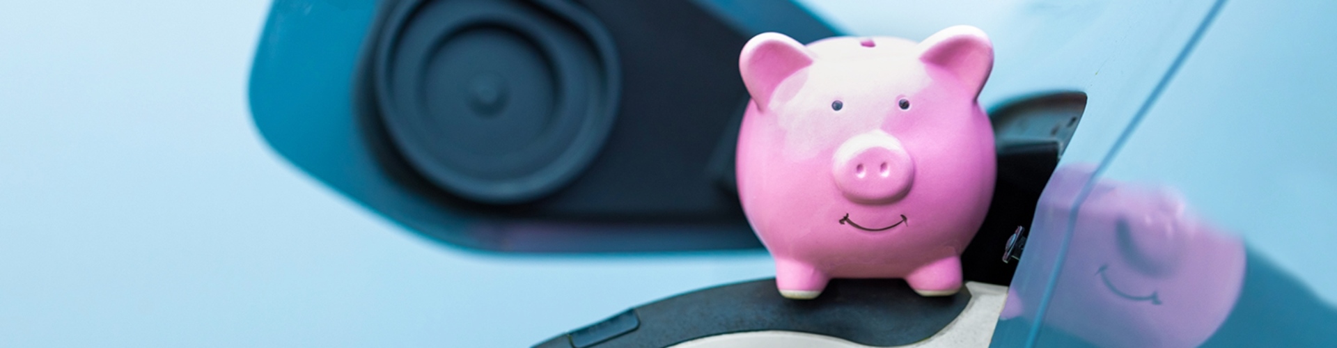 A pink piggy-bank sits on an EV's charging plug