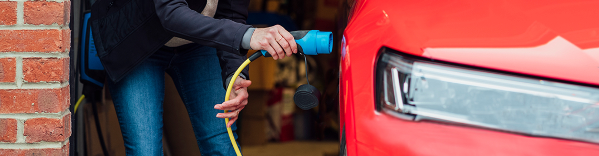 Someone plugging a cable into their EV in their home garage