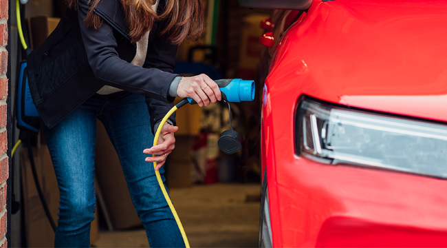 Someone plugging a cable into their EV in their home garage