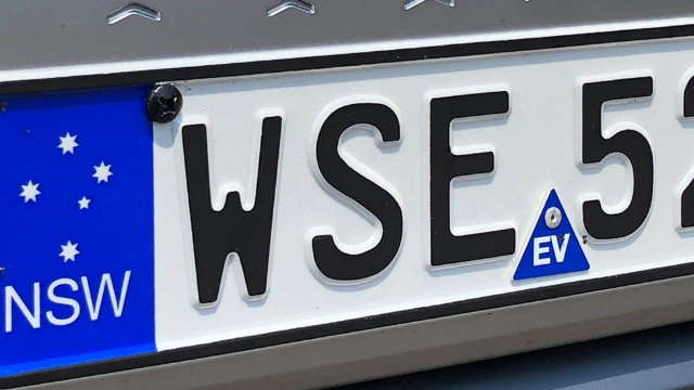A New South Wales vehicle number plate, with a blue EV safety sticker in the bottom middle of the plate.