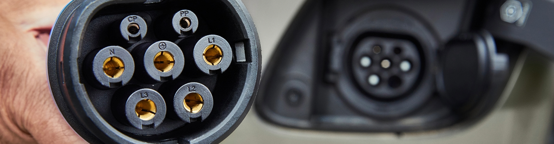 The end of an EV plug with the socket seen in the background