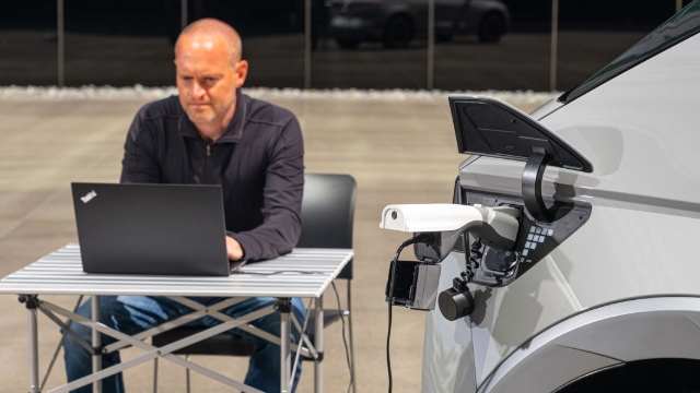 A person works at a laptop plugged into their car 