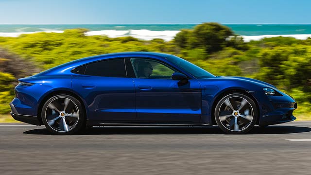 Blue 2022 Porsche Taycan driving next to beach