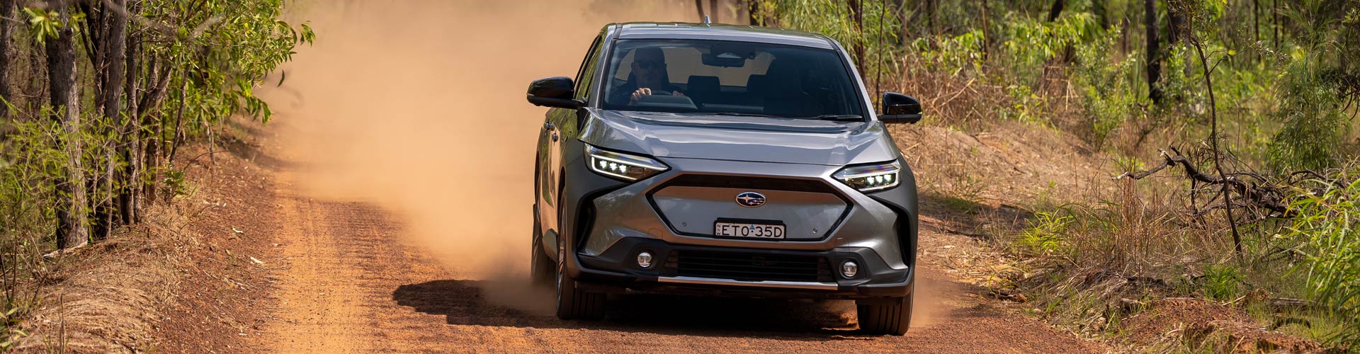 Silver Subaru Solterra driving on red dirt road