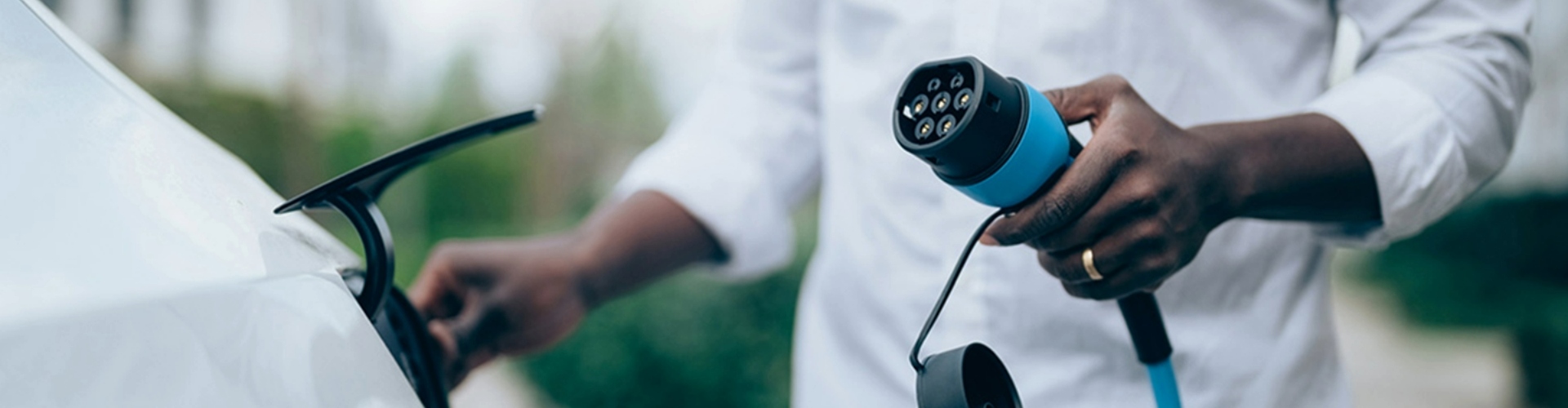 A man holding an electric vehicle (EV) charging cable, getting ready to charge a car.