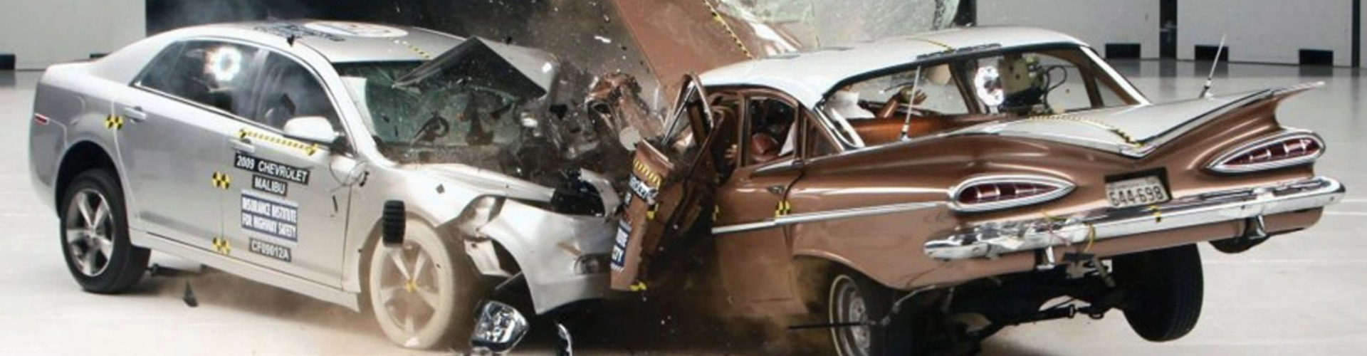 An old brown car and newer silver car in a head-on collision during a crash test.