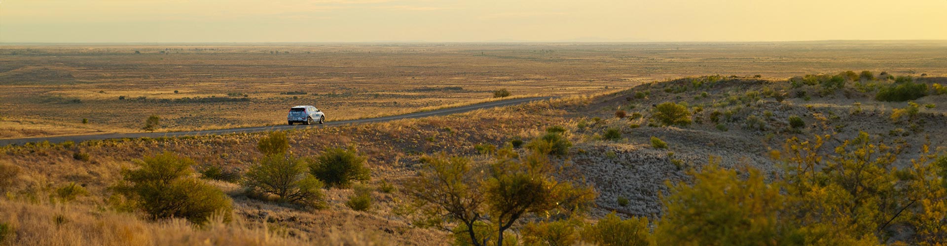 An EV drives across a vast desert landscape